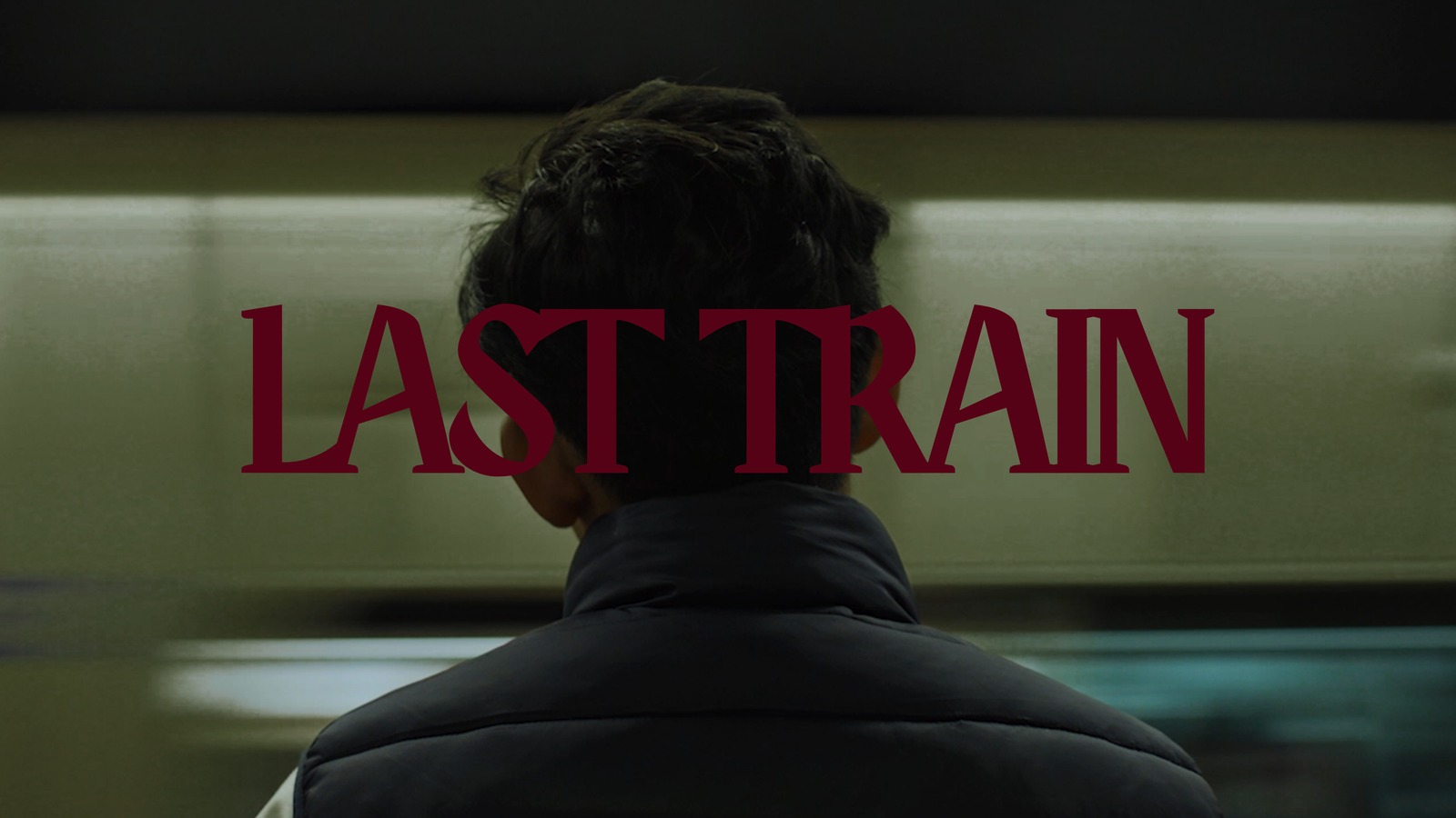 Last Train title slide, the back of a man's head at a tube platform as a train passes